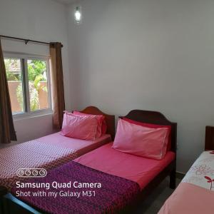 two beds with pink pillows in a room at Transit Studio Katunayake in Katunayake