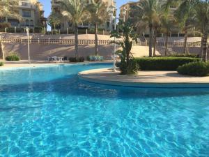 a swimming pool with blue water in a resort at Lovely New Alamein Chalet w/ Sandy Beach Access in El Alamein