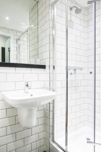 a white bathroom with a sink and a shower at Tune Hotel Liverpool in Liverpool