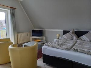 a bedroom with a bed and a tv and a chair at Bernsteinhaus Düne 10 in Zingst