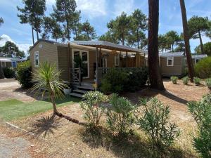 a tiny house in a yard with trees at Mobil-Home Camping Club 5* Montalivet in Vendays-Montalivet