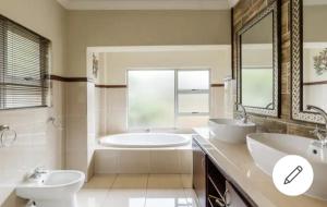 a bathroom with two sinks and a tub and a mirror at Jewel of Jozi in Edenvale