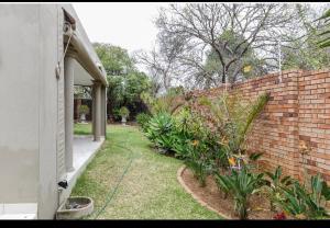 a backyard with a brick wall and some plants at Jewel of Jozi in Edenvale