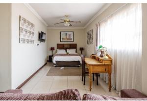 a bedroom with a bed and a desk and a table at Jewel of Jozi in Edenvale