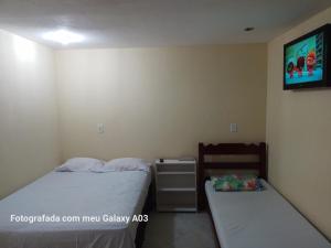 1 dormitorio con 2 camas y TV en la pared en Casa temporada paraíso, en Cabo Frío