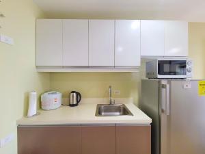 uma cozinha com armários brancos, um lavatório e um frigorífico em Suite 1 Bedroom with Seaview-Horizons 101 em Cebu