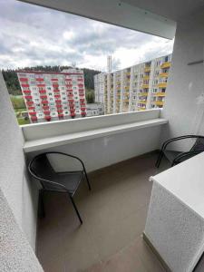 a balcony with two chairs and a large window at 3 izbový byt in Liptovský Mikuláš