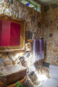 Baño de piedra con lavabo y pared de piedra en Gingerbread Restaurant & Hotel, en Nuevo Arenal