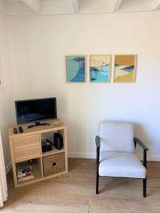 een woonkamer met een stoel en een televisie bij Petite Opale in Ambleteuse