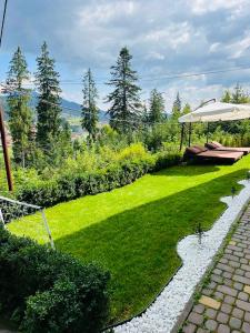 a garden with a table and an umbrella at Котедж Chalet Adriana in Bukovel