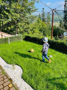 een kleine jongen die in het gras loopt met een voetbal bij Котедж Chalet Adriana in Boekovel