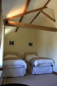 two beds in a room with wooden ceilings at The Granary Self Catering Cottage in Shrewsbury