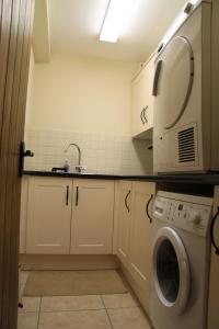 uma cozinha com uma máquina de lavar roupa e um lavatório em The Granary Self Catering Cottage em Shrewsbury