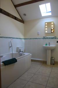 ein Badezimmer mit einer Badewanne und einem Waschbecken in der Unterkunft The Granary Self Catering Cottage in Shrewsbury