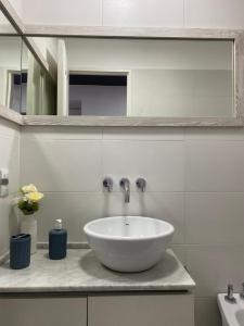 a bathroom with a white sink and a mirror at DEPARTAMENTO VERA MUJICA 4 COHERA PROPIA INCLUIDA in Rosario