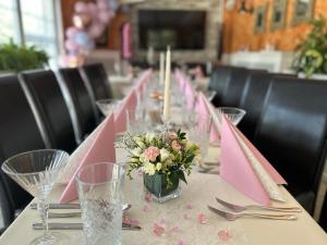 una mesa larga con servilletas rosas y flores. en Penzion Bystrica, en Považská Bystrica