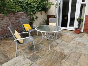 a glass table and chairs on a patio at Private garden apartment with secure parking in Southport