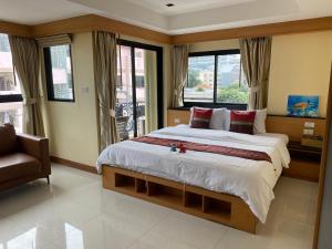 a bedroom with a large bed and a chair and windows at L18 residence แอลสิบแปด เรสซิเดนซ์ in Ban Zong Katiam