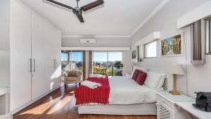 a white bedroom with a bed with a red blanket at Anchor Bay Workation in Cape Town