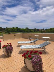 um pátio com dois bancos e flores num telhado em Incantevole attico con grande terrazza em Anzio