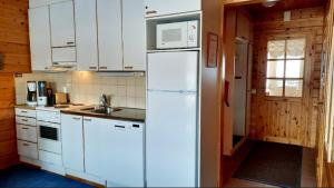 uma cozinha com armários brancos e um frigorífico branco em Apartment Urupaa em Saariselka