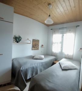 Apartment Urupaa في ساريسيلكا: غرفة نوم بسريرين وسقف خشبي