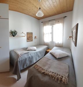 two beds in a room with white walls and wooden ceilings at Apartment Urupaa in Saariselka