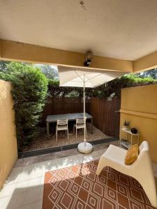 une terrasse avec un parasol, une table et des chaises dans l'établissement Studio Bord de Mer Boulouris à Saint Raphael, à Saint-Raphaël