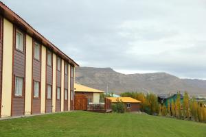 a building with a grassy yard next to a building at Hotel Picos Del Sur in El Calafate