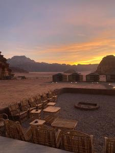 um grupo de cadeiras e mesas no deserto ao pôr do sol em Red Twilight Camp em Disah
