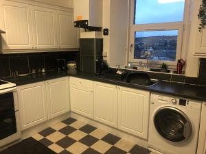 a kitchen with a sink and a washing machine at Captivating 2-Bed Apartment in Isle of Bute in Rothesay