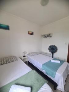 two beds in a room with white walls at Apartamento aconchegante in Jequié