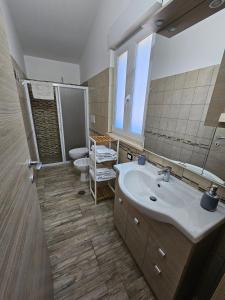 een badkamer met een wastafel, een toilet en een spiegel bij Villa Center appartamenti nel verde in città in Campobasso