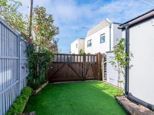 un patio trasero con una valla de madera y césped verde en Pass the Keys Bath Road Retreat 2 bedrooms with garden, en Cheltenham