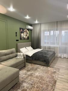 a bedroom with a bed and a couch and a window at Современная квартира в центре города in Kostanay
