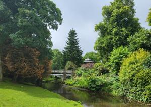 une rivière dans un parc avec un pont et des arbres dans l'établissement Impeccable 1-Bed Apartment in Buxton Town Center, à Buxton