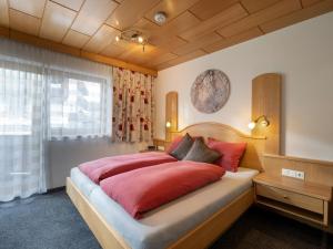 a bedroom with a large bed with red pillows at Haus Daniela in Wildschönau