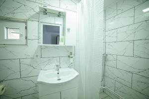 a white bathroom with a sink and a mirror at Cabana de Sub Deal Arieșeni in Arieşeni +15 photos