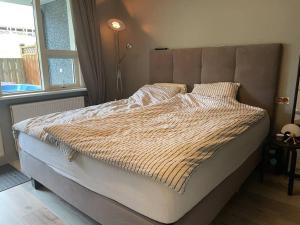 ein großes Bett in einem Schlafzimmer mit Fenster in der Unterkunft Bright beautiful flat on hilltop w hot tub in Hafnarfjördur