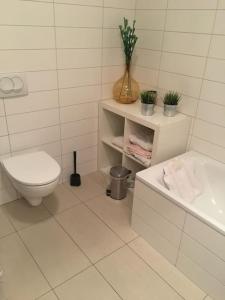 biała łazienka z toaletą i umywalką w obiekcie Bright beautiful flat on hilltop w hot tub w Hafnarfjördurze