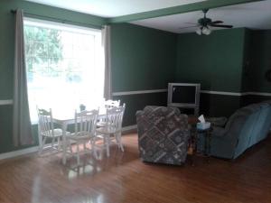 sala de estar con mesa, sillas y TV en Grumpy's Suite by the Lake, en Summerland
