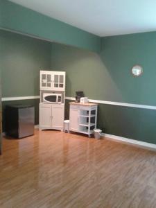 an empty living room with green walls and wooden floors at Grumpy's Suite by the Lake in Summerland +5 photos