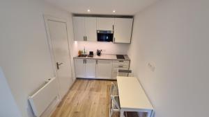a small kitchen with white cabinets and a table and chairs at Les Bossons Studio in Chamonix +5 photos