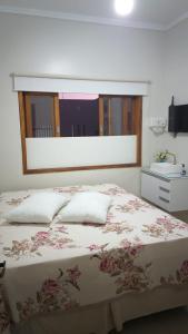 a bedroom with a bed with pink flowers on it at Sinta-se como se estivesse em sua casa! in Taubaté