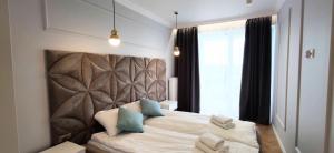 a bedroom with a bed with a headboard and a window at Apartamenty Baltic Sea Westin House 404 in Kołobrzeg +13 photos