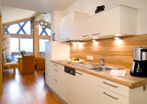 uma cozinha com armários brancos e um lavatório em Das Bäckergut am Haldensee em Haldensee