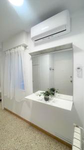 a white bathroom with a mirror and a potted plant at Sueños de Mar in Pineda de Mar