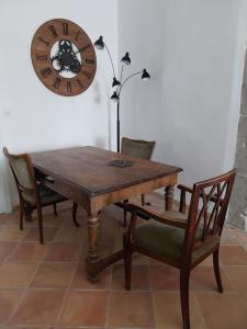 une table et des chaises en bois avec une horloge sur le mur dans l'établissement Château sur le Canal du midi proche de Carcassonne, à Trèbes