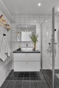 a white bathroom with a sink and a shower at Seaside city appartment in Tromsø