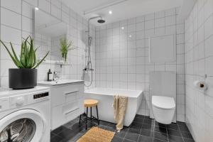 a white bathroom with a tub and a washing machine at Seaside city appartment in Tromsø